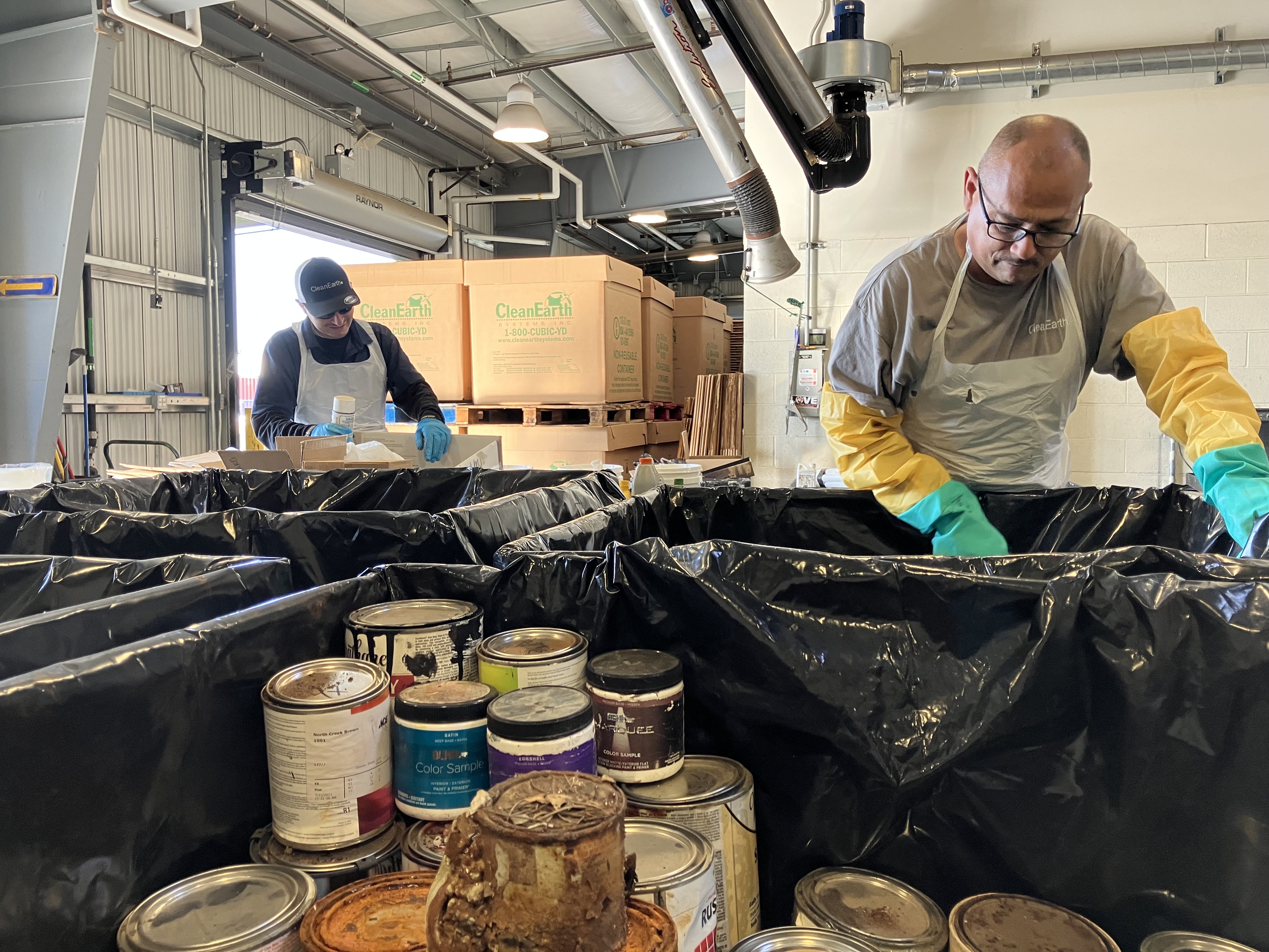 Technicians sort hazardous waste at a drop-off facility.