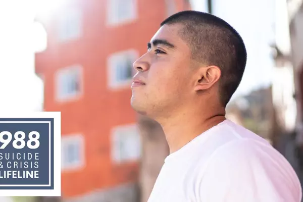 A young man looks hopefully toward the sky outside, with 988 Crisis and Suicide Prevention Hotline logo added.