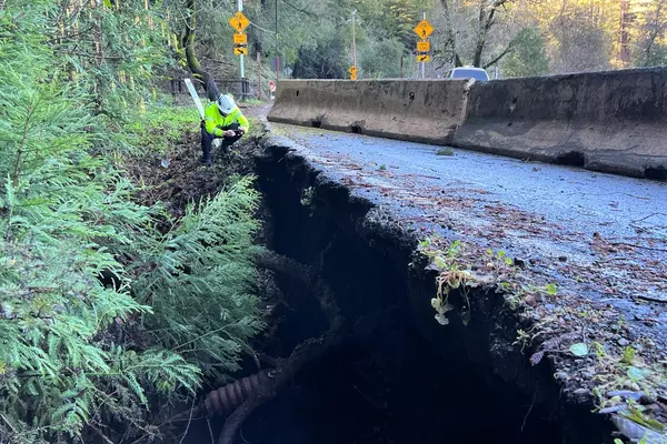 A County employee inspects storm damage to Bear Creek Road near Los Gatos.