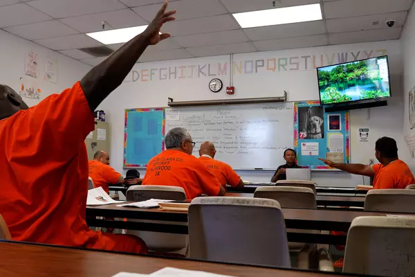 A program participant raises his hands in a classroom