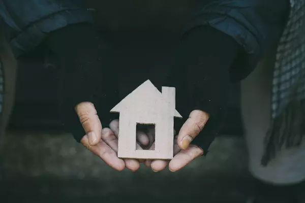 Image of a person holding a small cutout of a cardboard house.