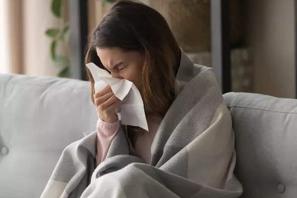 sick girl blowing nose feeling sick