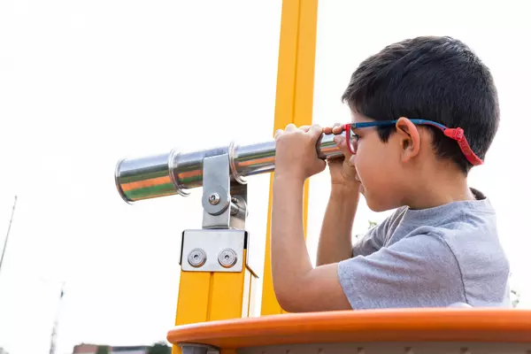 A young boy peers through a telescope.