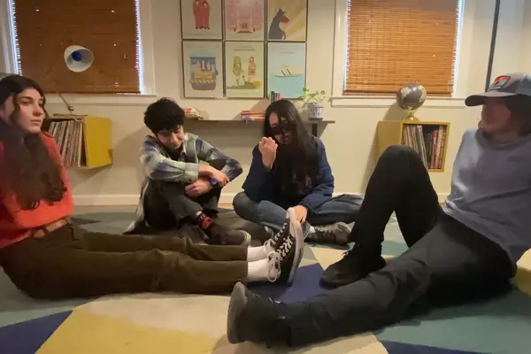 Four kids sitting on the floor talking