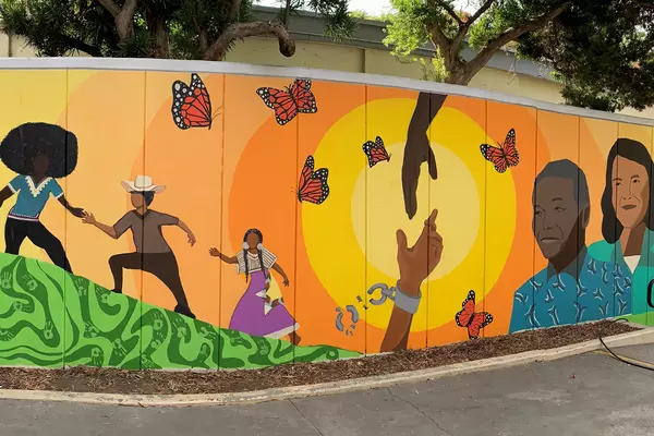 Mural of people playing, butterflies, hands joining