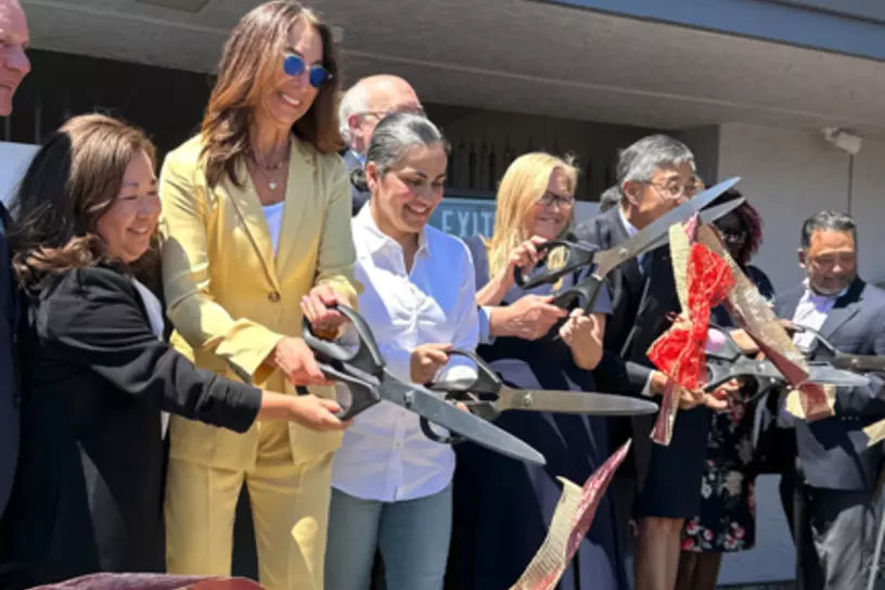 people cutting ribbon with giant scissors