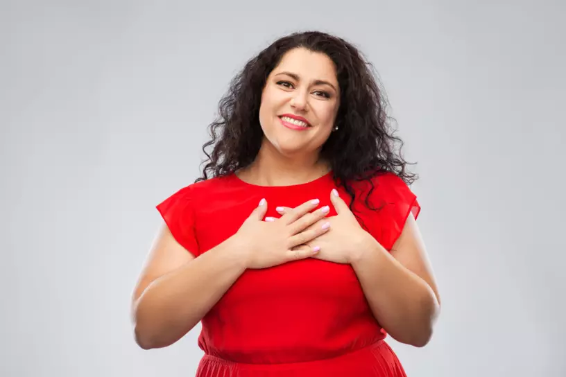 Woman smiling with both hands placed over her heart