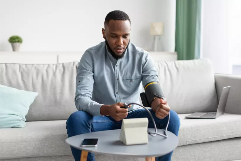 Black man taking blood pressure at home