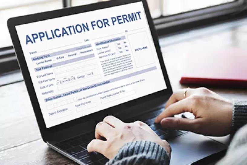 Hands on a laptop with Application for Permit on screen