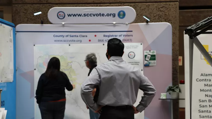 Person observing 2 other people looking at the County of Santa Clara district map