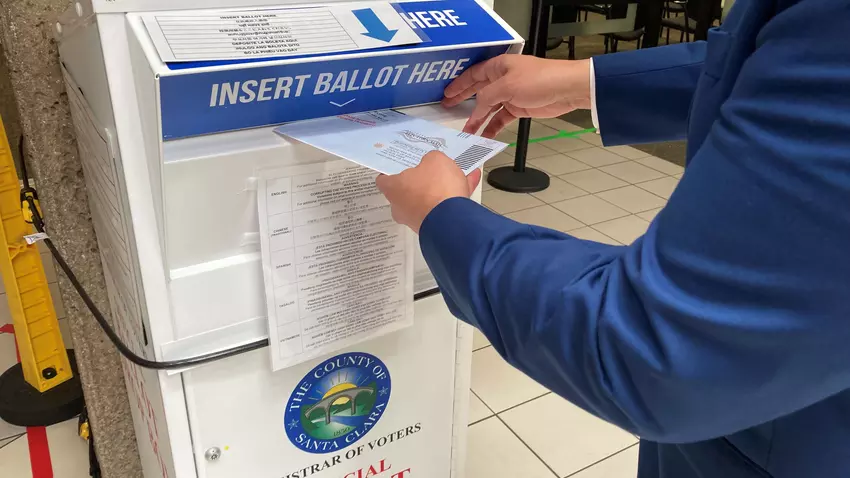 A voter dropping his ballot into the Registrar of Voters Official Ballot Drop Box.