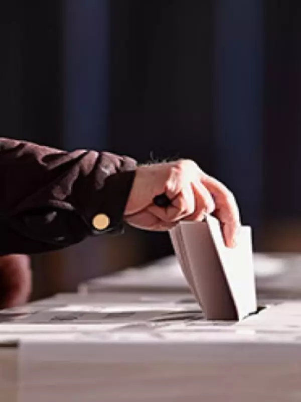 A person dropping their vote into a box