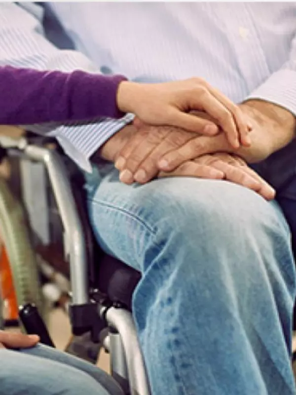A person in a wheelchair being comforted.