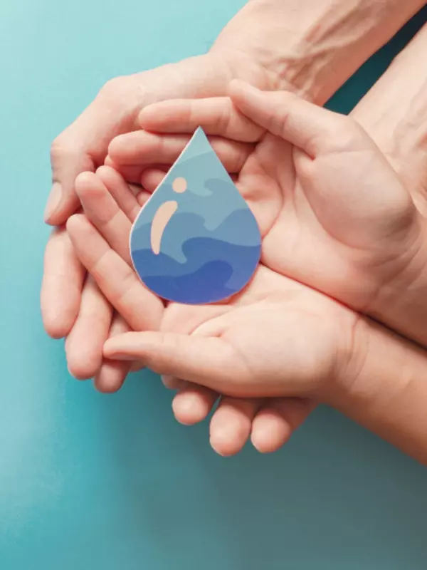 Two pair of hands holding a cut out water drop