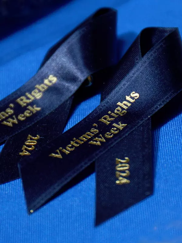 Dark blue ribbons with gold lettering for 2024 Victims' Rights Week on a blue tablecloth