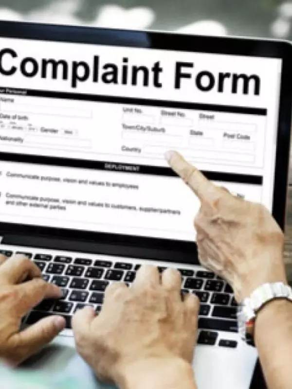 Man looking at a complaint form on his laptop with a woman pointing to a section of the form