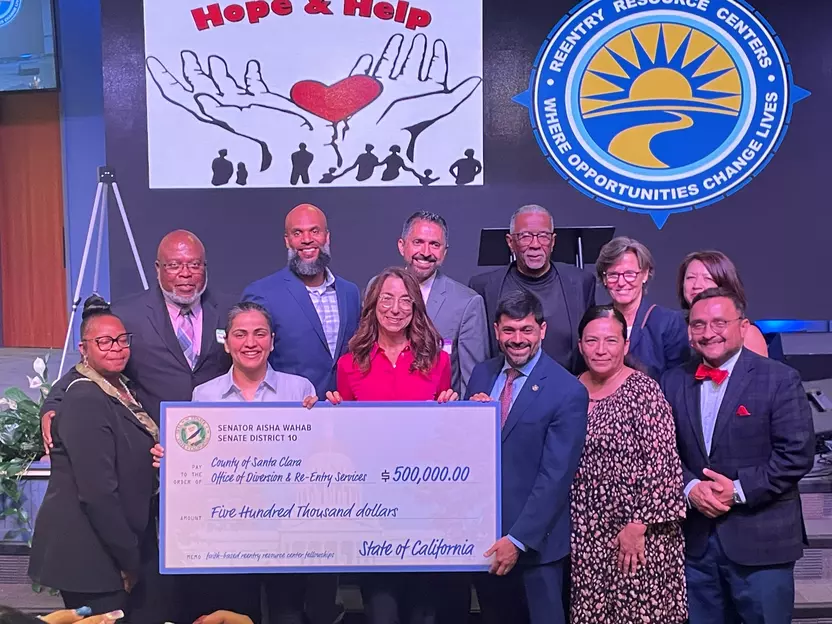 Supporters, advocates, and leaders hold a large check