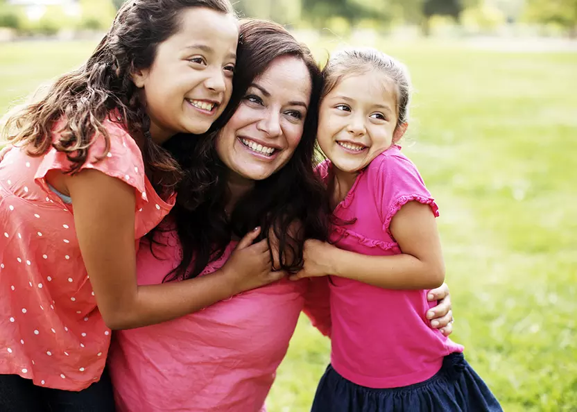 mom-and-daughters-in-park-hugging