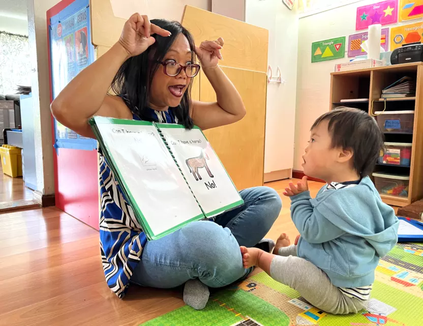 A childcare worker reads to a young child.