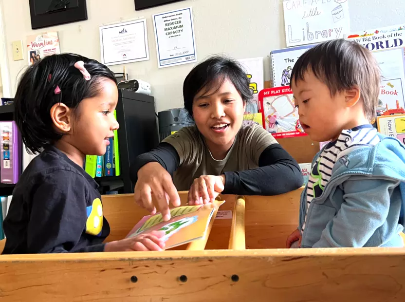 A childcare worker plays with two young children.