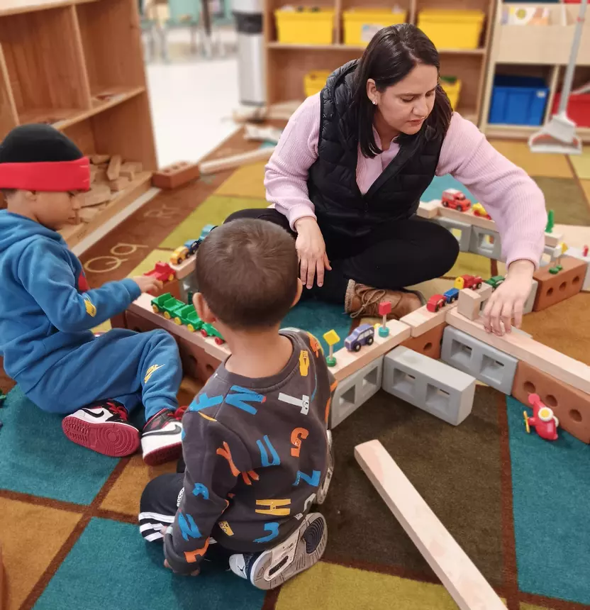 A childcare worker plays with two young children