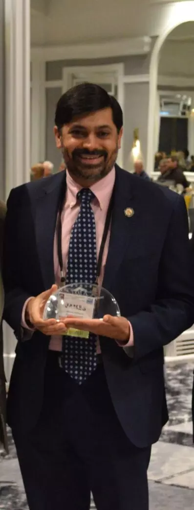 man wearing suit holding award