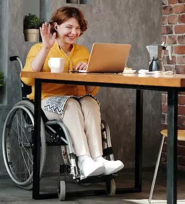 Woman in a wheelchair waving at people on a virtual call