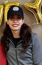 Salezka in a grey zip up jacket and black baseball cap smiling at camera