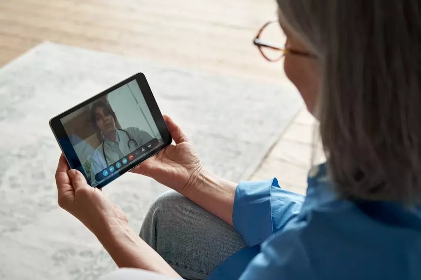 Telehealth session with woman holding a device with image of female physisican