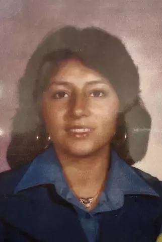 Image of an 18-year-old Latina woman, named Elena  Mena, wearing a necklace and gold earrings, blue dress shirt with a blue jacket. 