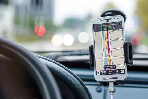 A cell phone with GPS open is attached to a phone holder in a car 