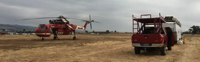 Helicopter and pickup truck on a plain field setting up a helitack base at San Martin Airport
