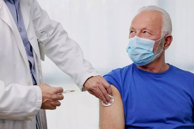 Doctor giving shot to senior male