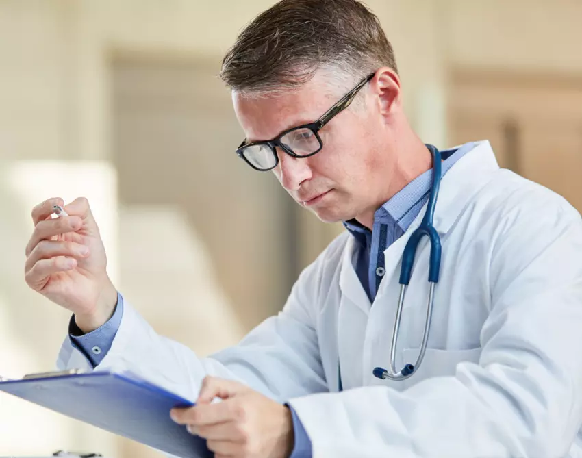 Male doctor reading off clipboard